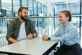 Foto av to kolleger som sitter og prater.